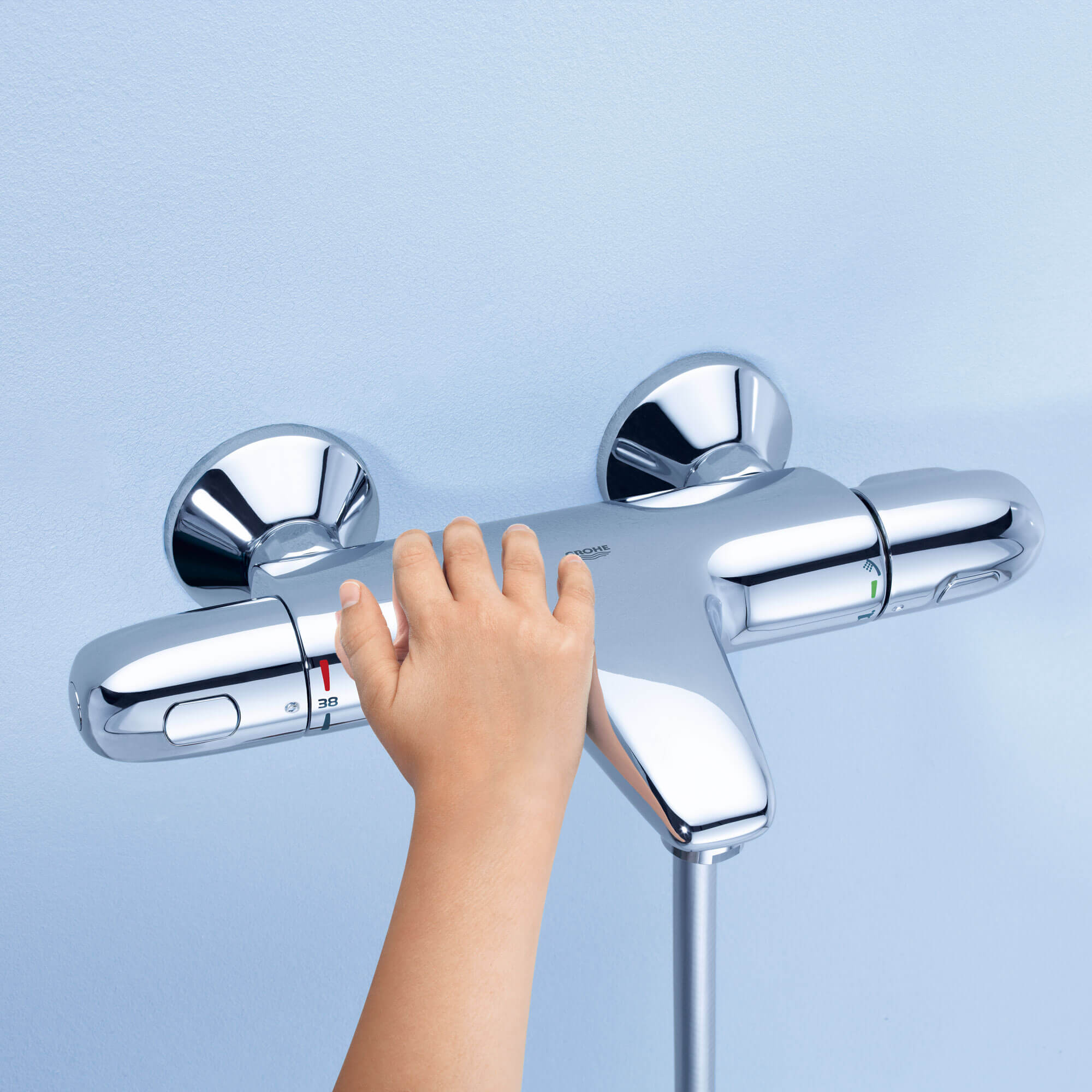 A child's hand reaching for a thermostatic knob.
