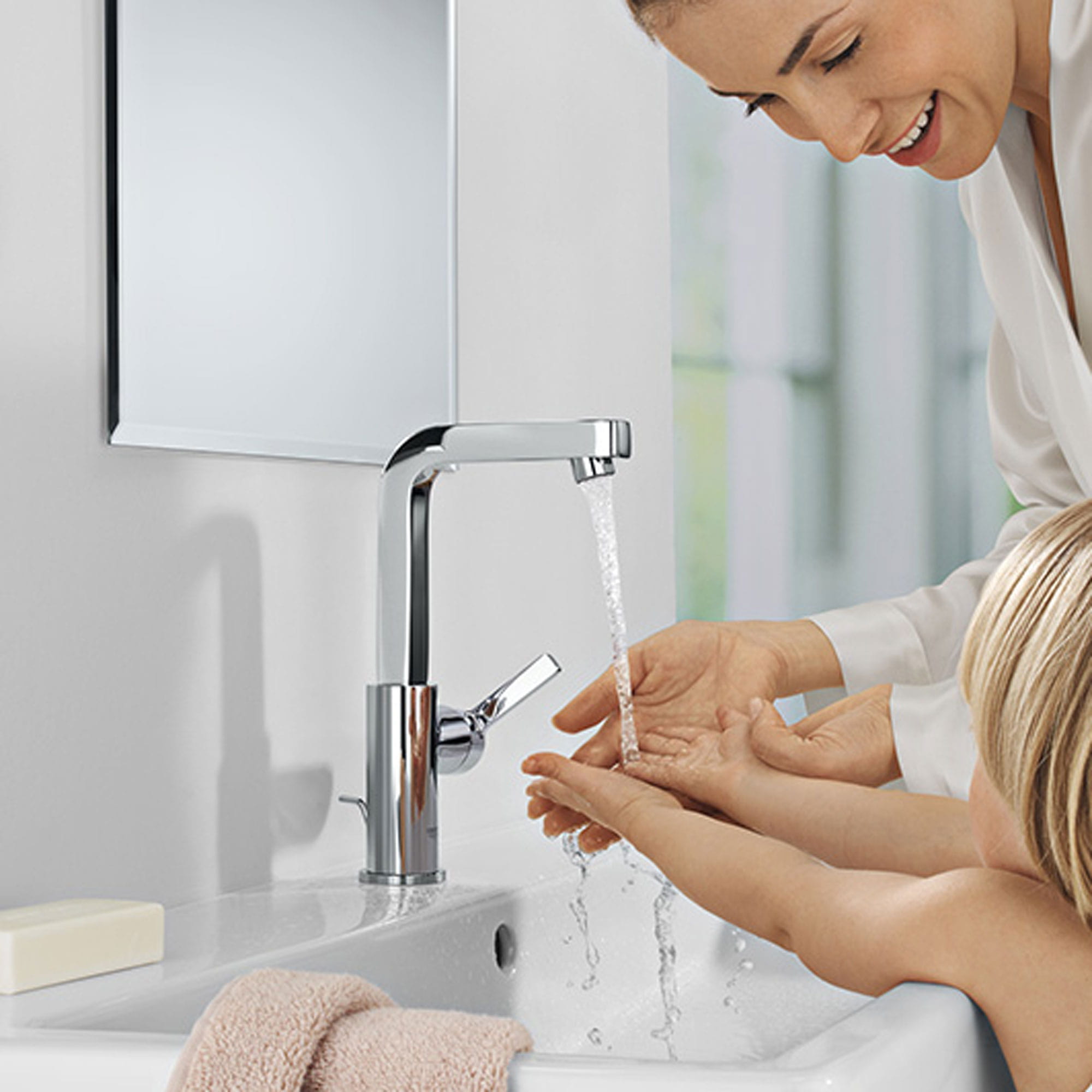 A women washing her and her child's hands under a grohe faucet.