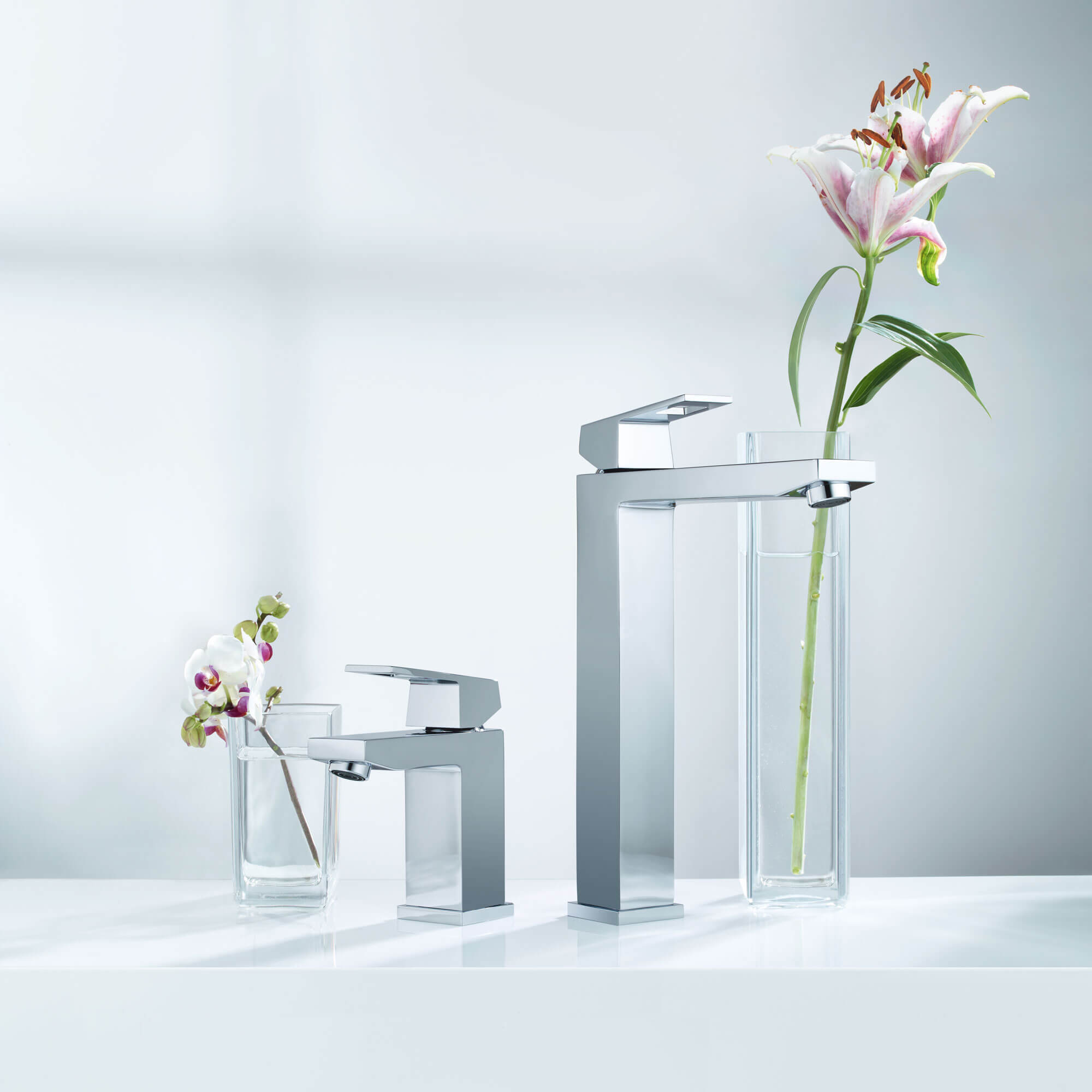 Une paire de robinets Grohe à côté de vases remplis de fleurs.