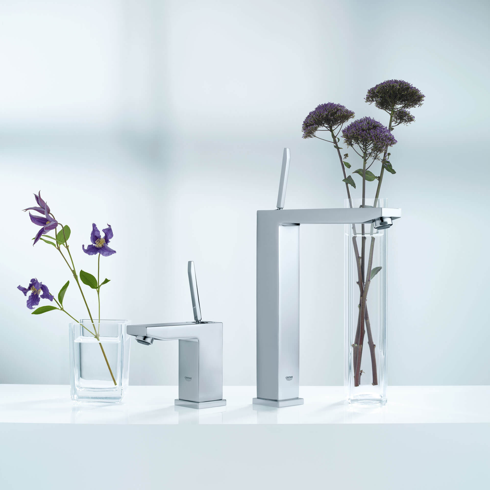 Une paire de robinets Grohe à côté de vases remplis de fleurs.