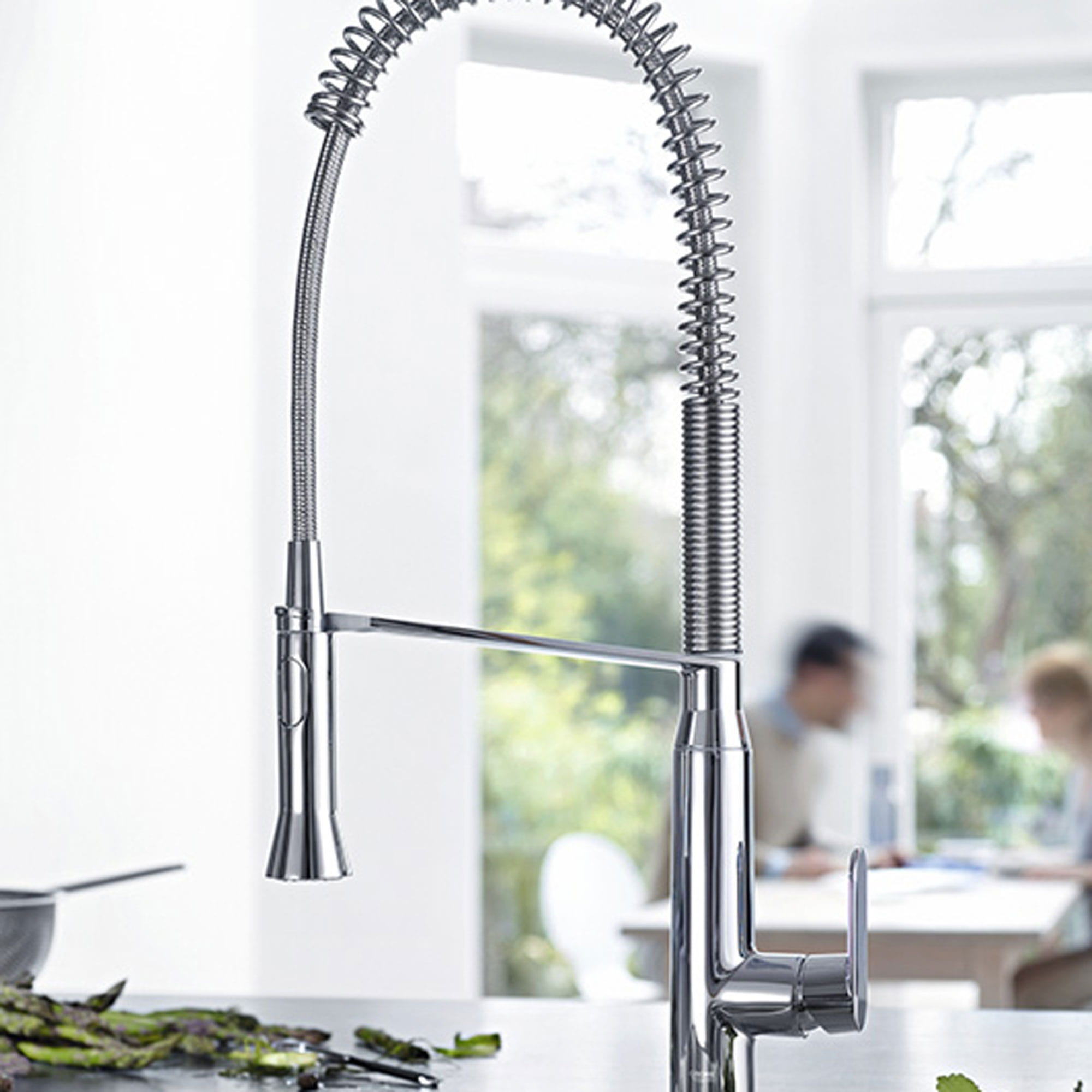 kitchen faucet with two people in blurred background