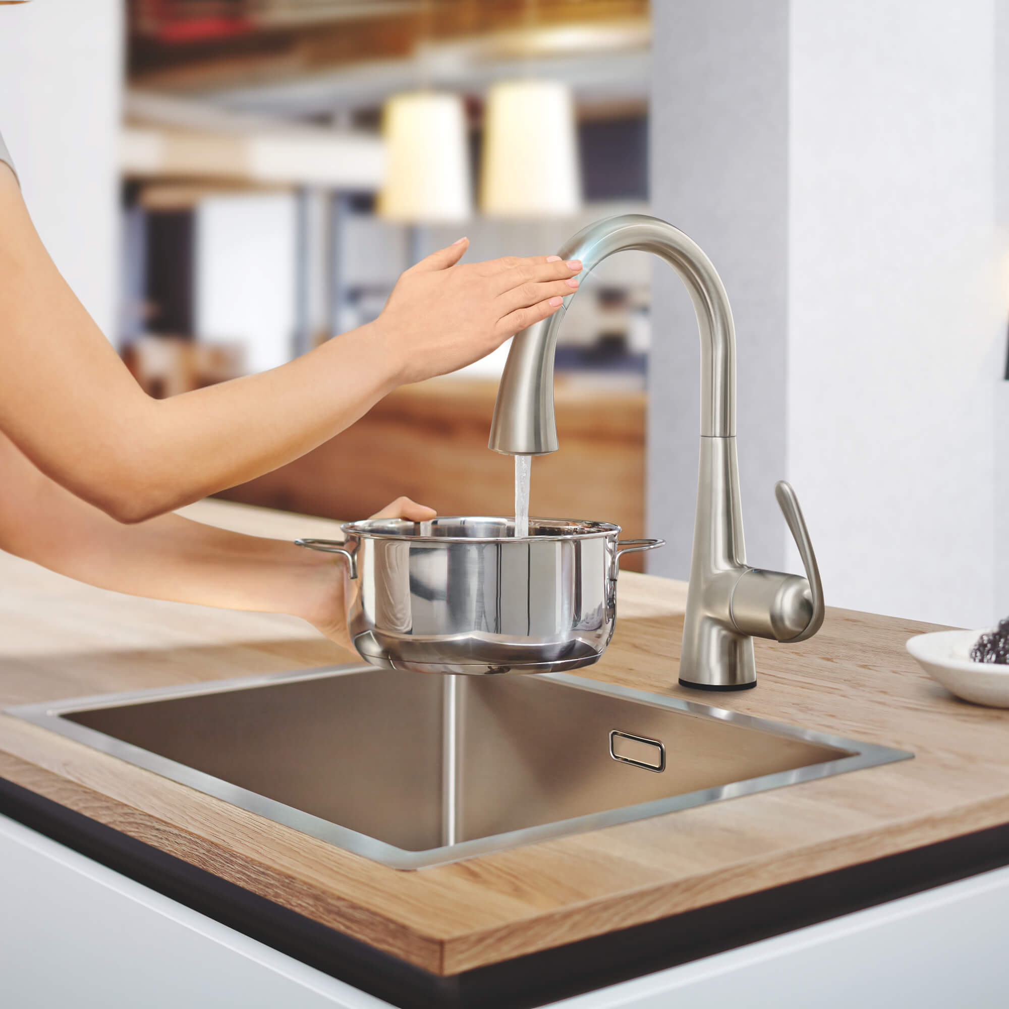 Hand using  touch function for GROHE Zedra Touch Kitchen Faucet to fill pot with water