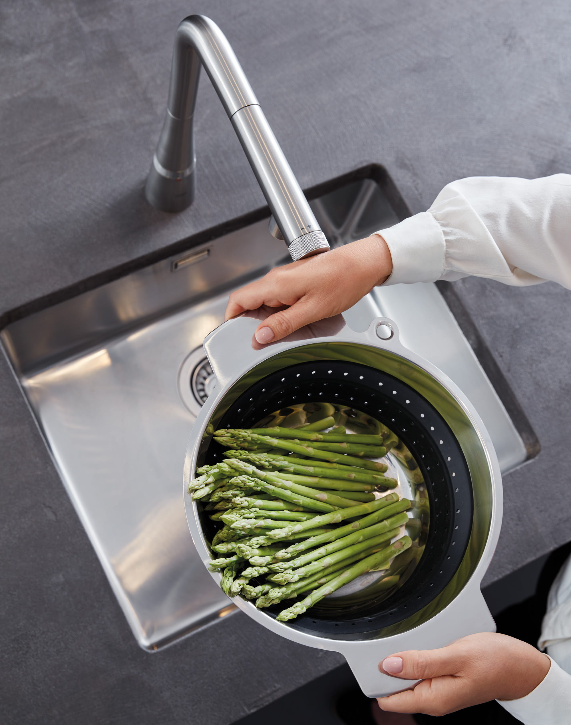Touch faucet in use washing asparagus in the kitchen