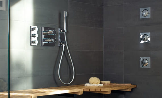 gray shower with wall jet spray, handshower, wall controls, and wooden bench