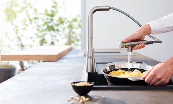 Woman using SmartControl kitchen faucet to wash food